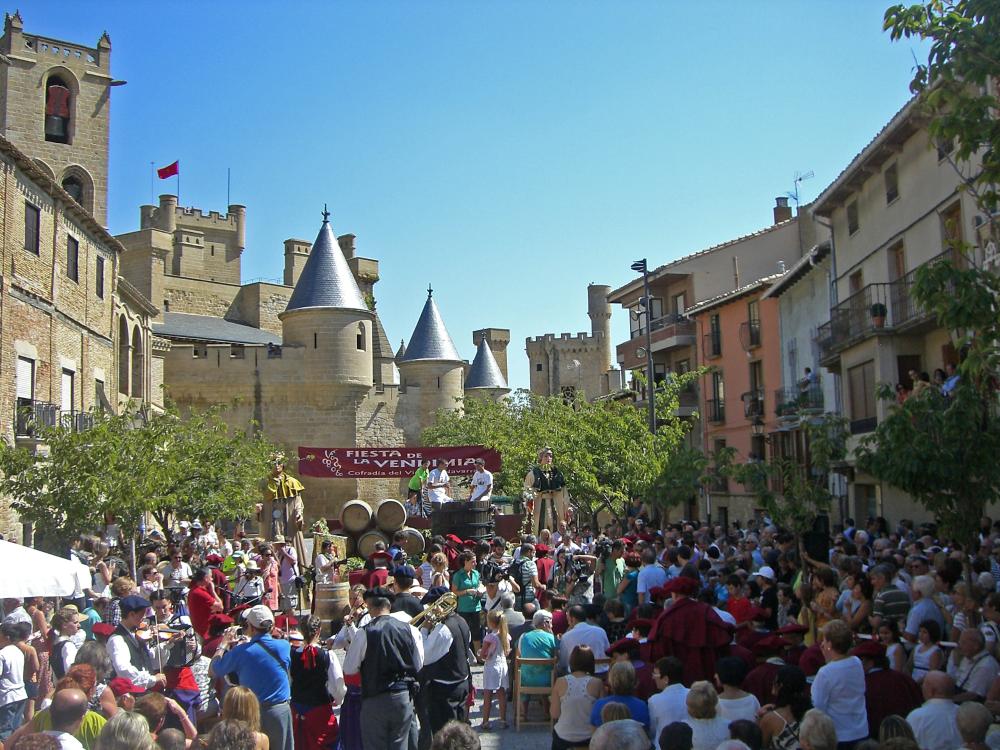 desfile de niñas vestidas con ropa antigua llevando uva en cestos. Castillo de Olite al fondo